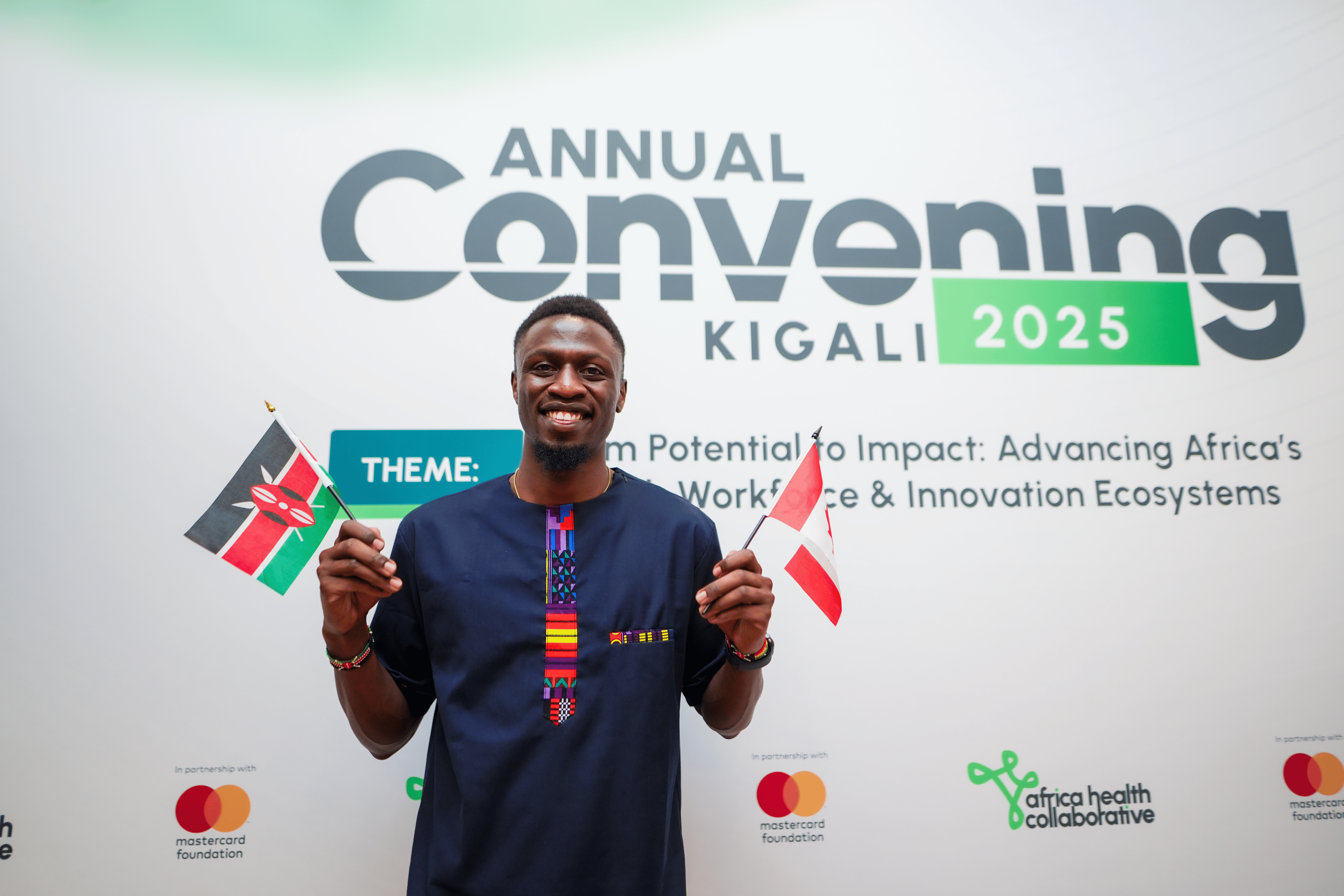John Nyagaka standing before the 2025 AHC Convening, Kigali, with a Kenyan flag and a Canadian Flag